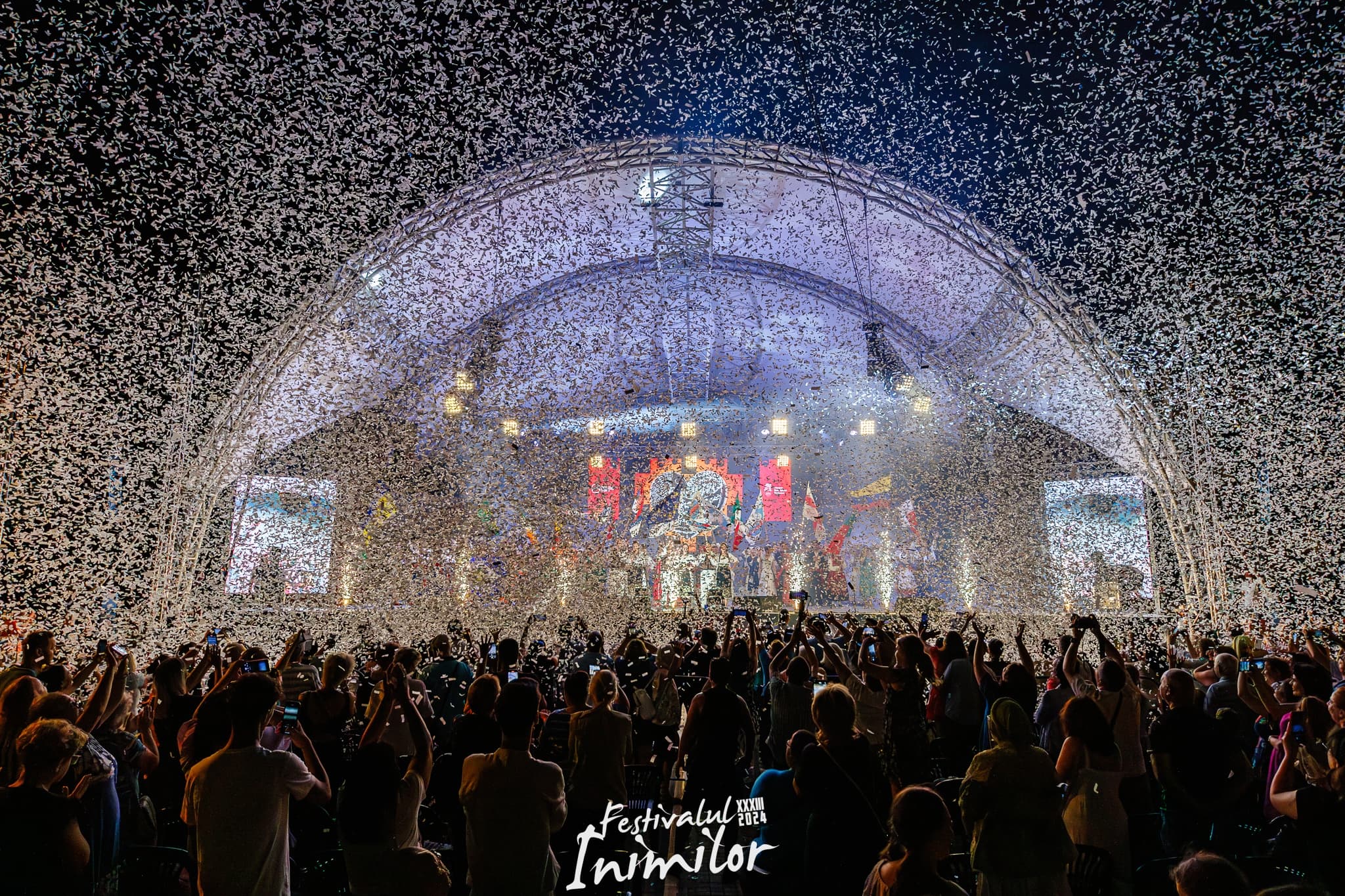 Confetti finale la Festivalul Inimilor — scena de noapte cu public ridicând mâinile spre cer